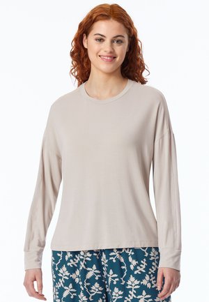 Hellbeige langärmliges Shirt mit rundem Ausschnitt und lockerem Schnitt. Weiche Textur, keine sichtbaren Muster. Kombiniert mit gemusterten blauen Hosen.