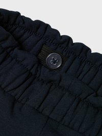 Cinturilla de tejido marino con textura fruncida y un botón negro con diseño de flor, que mejora el ajuste seguro.