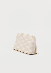 Trousse de maquillage beige avec un motif répétitif du logo "MK", fermeture éclair dorée, et forme rectangulaire aux bords arrondis, posée sur une surface blanche.