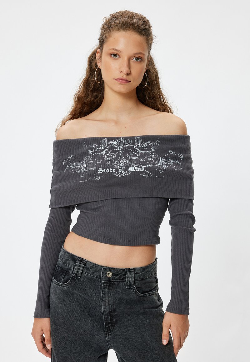 Grauer gerippter Crop-Top mit schulterfreiem Design, langen Ärmeln und einem weißen Grafikdruck mit dem Text "State of Mind" in der Mitte.