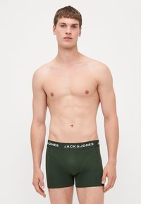 Grüne Baumwoll-Boxershorts mit einem breiten schwarzen Bund, der "JACK & JONES" in weiß zeigt. Einfaches Design, figurbetonte Form und glatte Textur.