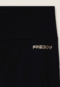 Leggings neri realizzati in tessuto morbido, con un ampio elastico in vita e il logo dorato "FREDDY" sul lato. Design elegante e aderente.