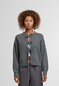 Grauer Strickcardigan mit langen Ärmeln, offener Vorderseite und Krawattendetails am Ausschnitt. Weicher Stoff mit lässiger Passform.
