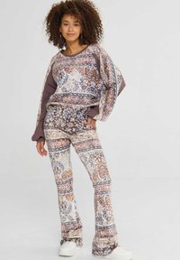 Twee-delige outfit bestaande uit een gebloemde sweatshirt en flared broek in pastelkleuren, met bloemmotieven en een relaxed fit.