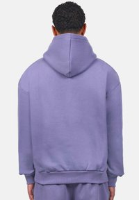 Pullover-Hoodie in helllila, mit einer großen Kapuze, gerippten Bündchen und Saum sowie einer weichen Fleece-Textur. Einfaches, lässiges Design.