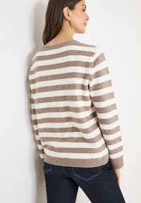 Maglione a righe in marrone chiaro e crema, realizzato in morbido tessuto a maglia. Presenta una scollatura rotonda e polsini e orlo a coste.