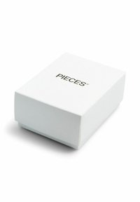 Boîte rectangulaire blanche à la texture lisse, portant le mot « PIECES » en lettres noires sur le dessus, design minimaliste.