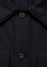 Granatowa kurtka z dużym kołnierzem, dwoma czarnymi guzikami z przodu i subtelnie widocznymi detalami przeszyć. Gładka tekstura o matowym wykończeniu.