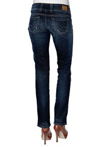 Mörk tvättade denimjeans med slim fit, med horisontell söm och två bakfickor. Matchas med beige högklackade skor.