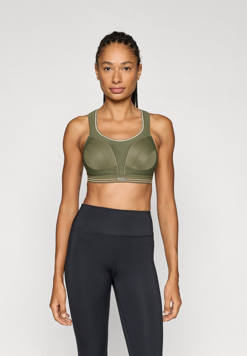 Αθλητικό σουτιέν σε ελιάς πράσινο με δομημένο σχεδιασμό, καλούπια και αντίθετες ραφές. Συνδυάζεται με εφαρμοστά μαύρα κολάν.