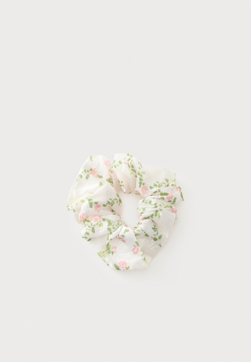Λευκό υφασμάτινο scrunchie με ροζ λουλούδια και πράσινα φύλλα σε ανοιχτό φόντο.