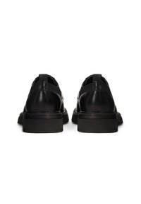 Scarpe nere in pelle con un design elegante, suola robusta, inserti laterali elastici e una texture liscia e lucida.