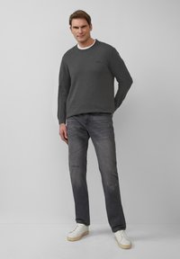 Grijze gebreide trui met een ronde hals, gecombineerd met vervaagde grijze spijkerbroek met versleten details, en witte sneakers. Eenvoudige en casual uitstraling.