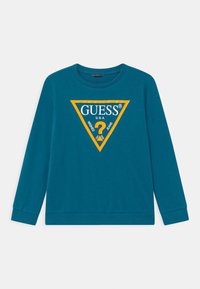 Sudadera azul verdoso con mangas largas, cuello redondo y un gráfico triangular naranja en la parte frontal que presenta la marca "GUESS®" y texto.