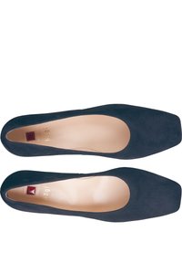 Escarpins en daim bleu marine avec un bout carré, un intérieur beige lisse et un petit détail d'accent rouge sur la semelle intérieure.