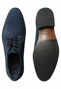 Granatowe zamszowe buty z prostym sznurowanym wzorem, zaokrąglony czubek i gładka skórzana wyściółka. Gumowa podeszwa posiada teksturowany wzór dla lepszej przyczepności.