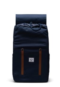 Mörkblå ryggsäck med rulltoppdesign, tygutsida, bruna läderremmar, framficka och en märkesetikett på botten.