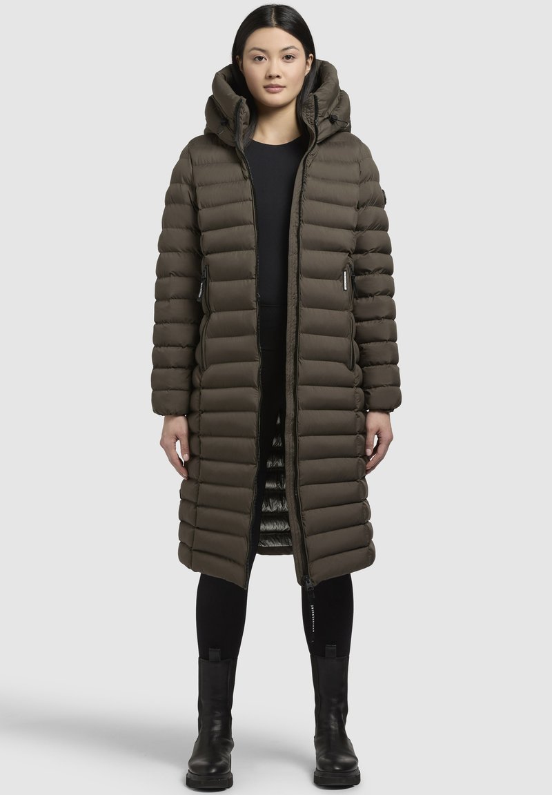 Zateplený dlouhý kabát v olivově zelené barvě s kapucí, s předním zipem, bočními kapsami a hladkou texturou. Lemovací detaily podél švů.