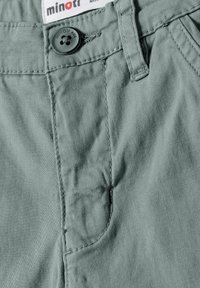 Grüne Baumwollshorts mit einer glatten Textur, ausgestattet mit einem schwarzen Knopfverschluss, Seitentasche und sichtbaren Nähdetails. Markenlabel oben.