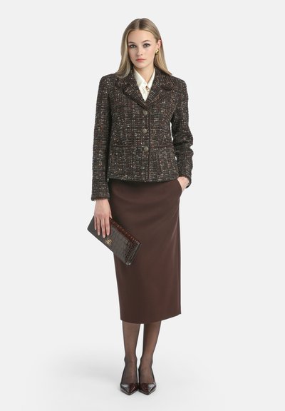 Tweed-takki tummissa sävyissä, jossa on monivärisiä pilkkuja, nappikiinnitys, yhdistetty ruskean kynähameen, kiiltävien korkokenkien ja lompakko-kosmetikkatyynyn kanssa.