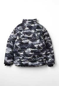 Puffa bunda v námornatě modrém a šedém maskáčovém vzoru, s vysokým límcem, prošívanou strukturou a logem poblíž výstřihu.