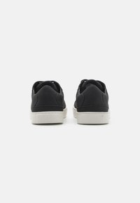 Sneakers in pelle nere con finitura liscia, suola in gomma bianca e design minimalista. Presentano un contorno cucito e chiusura con lacci.