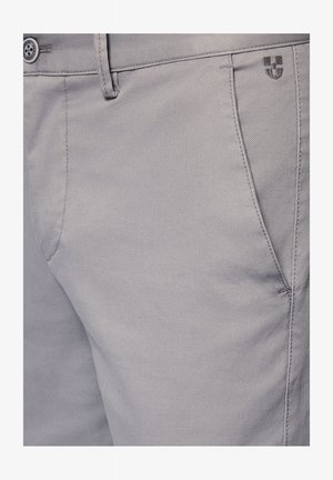 Jasnoszare szorty z tkaniny, charakteryzujące się teksturowanym splotem, przednią kieszenią i małym logiem w okolicy pasa.