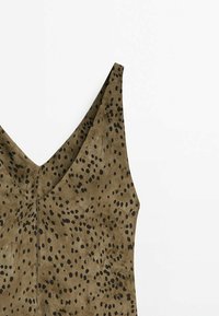 Robe sans manches brune avec un décolleté en V profond, présentant un tissu texturé et un motif à taches noires sur l'ensemble. Fermeture éclair dans le dos.