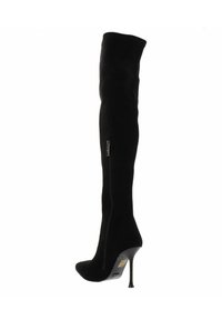 Zwarte laarzen tot boven de dij, gemaakt van zachte stof met een slank ontwerp, met een spitse neus en een hoge stilettohak. Detail van een zijrits.