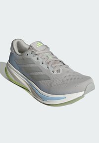 Szare buty sportowe z oddychającą siateczką na górze, charakterystycznym wzorem trzech pasków, amortyzowaną podeszwą w zielono-niebieskim kolorze oraz teksturowanymi sznurówkami.