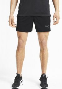 Svarta sportshorts med elastisk midja, lättviktig tyg och en subtil grå Puma-logga på sidan. Kombineras med svarta sneakers.