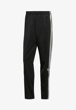 Pantalon de sport noir avec des bandes blanches sur les côtés, taille élastique, poche zippée et écusson du logo Adidas sur la jambe droite.