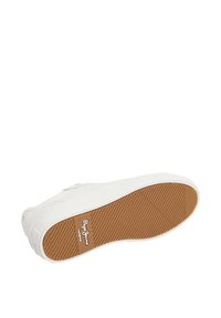White sneaker with a textured rubber sole and a beige accent. Features a low-profile design and branding on the side of the sole.