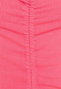 Różowy prążkowany materiał z pionowymi paskami i widocznymi detalami szycia wzdłuż środka. Miękka tekstura z delikatnym rozciągnięciem.