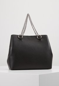 Sac cabas en cuir noir texturé avec des anses en chaîne argentée, comportant des anneaux ronds aux points d'attache et une forme structurée.
