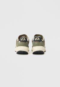 Zelene sneakers od suedea i mrežice s bijelom potplatom i crnim gumiranim gaznim slojem. Na peti ima VEJA oznaku. Minimalistički dizajn.