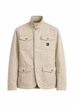 Beżowa bawełniana kurtka ze stójką, cztery przednie kieszenie z patkami zapinane na guziki oraz mała czarno-złota naszywka z logo na piersi.