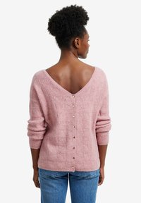 Rosa gestrickter Pullover mit V-Ausschnitt und einem strukturierten Blattmuster. Verziert mit goldenen Knöpfen entlang des Rückens und gerippten Bündchen.