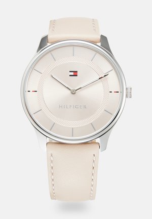 Rond zilveren polshorloge met beige leren band, minimalistische crèmekleurige wijzerplaat, zilveren uurmarkeringen en klein Tommy Hilfiger-logo boven het midden.
