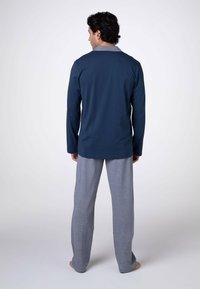 Camicia a maniche lunghe blu navy con colletto grigio, abbinata a pantaloni del pigiama grigio chiaro. Il tessuto sembra morbido e confortevole, ideale per rilassarsi.