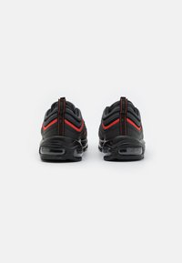 Black athletic shoes with red accents, a rounded design, visible air cushioning in the sole, and textured upper material.