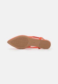 Red pointed-toe flat shoe lying on its side showing the textured rubber sole and size number 37.