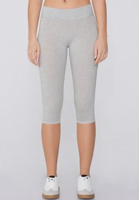 Szare legginsy capri z szerokim, elastycznym pasem. Wykonane z miękkiego, elastycznego materiału, sięgającego do połowy łydki, w zestawie z białymi sneakersami.