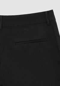 I pantaloni neri presentano una texture di tessuto liscia, una vestibilità standard e una singola tasca posteriore con una cucitura elegante.
