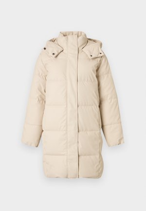 Bēšs pūkains mētelis ar augstu apkakli, rāvējslēdzēja aizdari un noņemamu kapuci. Aprīkots ar šūtiem laukumiem un garām piedurknēm ar gludu tekstūru.