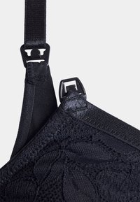 Cinta de soutien em renda preta e rede com ajustadores; apresenta um padrão floral texturizado e uma faixa elástica para melhor ajuste.