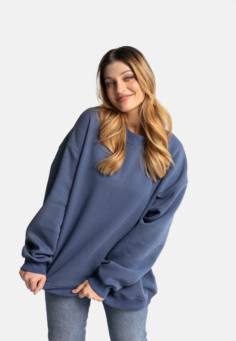 Niebieski, wielki sweatshirt wykonany z miękkiego materiału, z długimi rękawami i luźnym krojem. W połączeniu z niebieskimi dżinsami, z minimalnymi detalami.