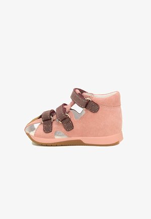 Roze suède schoen met drie donkerroze bandjes, open teen ontwerp en rubberen zool. Heeft uitsparingen voor ventilatie.