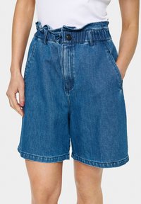 Džinsu šorti ar tumši zilu nokrāsu, augstu jostasvietu ar viļņotu joslu, priekšējo pogu aizdari un sānu kabatām. Apakšdaļā vienkāršs apmale.