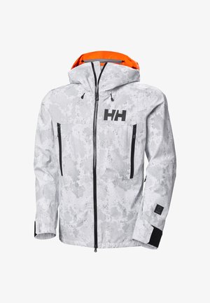 Witte camouflagesjas met zwarte ritsen en accenten. De capuchon heeft een oranje voering. Twee voorzakken met rits en zichtbaar logo.